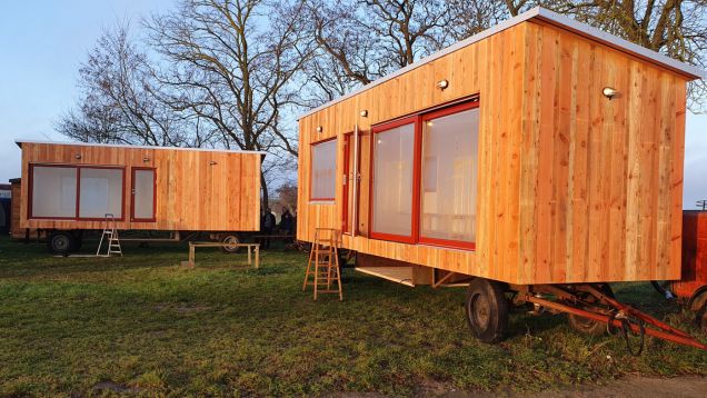 Foto von zu Bildungswagen umgebauten Bauwagen in Holzoptik, die in den Waldgärten Kyritz auf einer grünen Wiese stehen