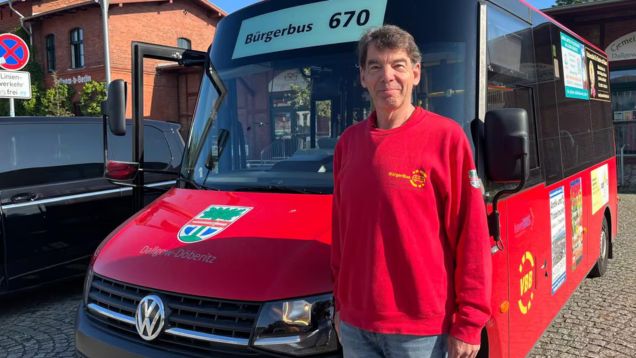 Foto von ehrenamtlichem Fahrer Bernd Hildebrandt beim Bürgerbus-Verein im Havelland vor seinem roten Bürgerbus stehend