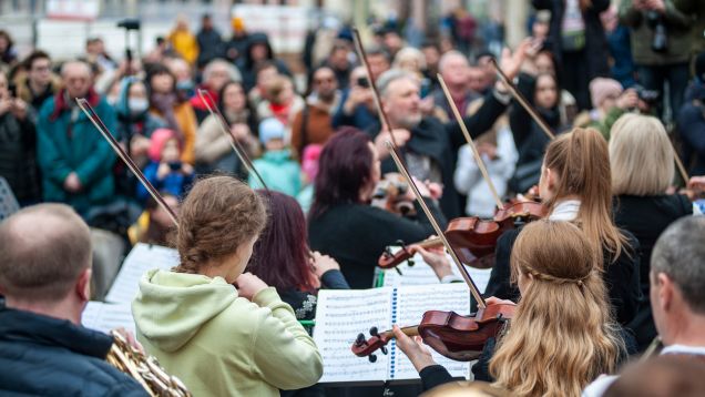 Symbolfoto für Benefizkonzert - Streicher eines Orchesters open Air vor Publikum im Hintergrund