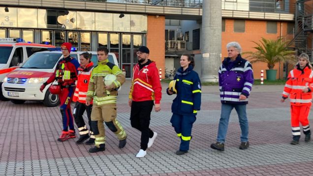 Foto von jungen Erwachsenen mit Ehrenamtlern des Katastrophenschutzes auf einem Platz in Cottbus