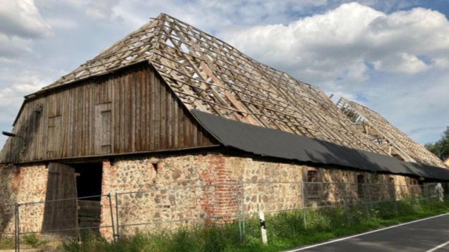 Foto vom Schafstall in Schlamau mit sichtbarer Dachkonstruktion vor grauem Himmel