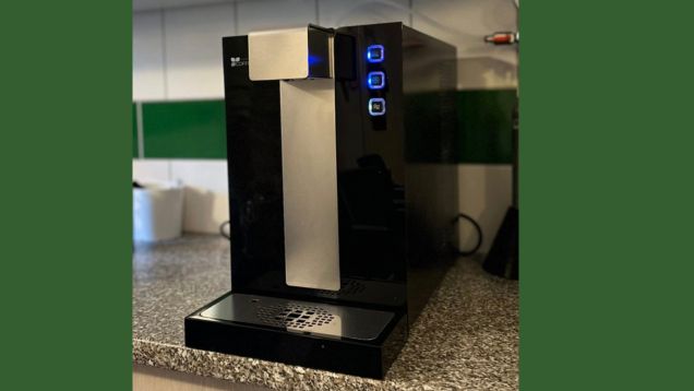 Foto vom schwarzen Wasserautomaten auf einer Küchenplatte stehend